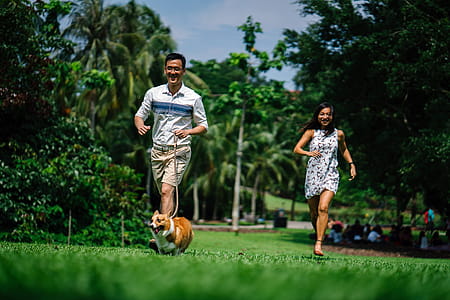 Man and Woman Running Near Green Leaf Trees Photo thumbnail