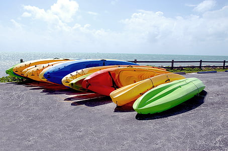 aligned assorted-color kayaks on gray seashore during daytime photo thumbnail