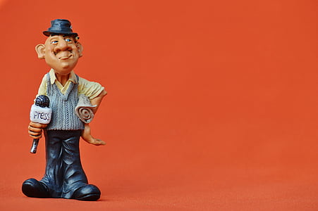 brown and black ceramic man miniature standing on orange surface thumbnail