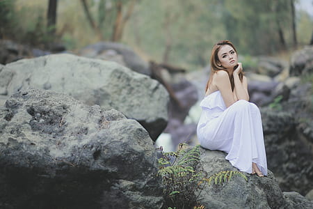 woman wearing white strapless dress sitting on the stone thumbnail