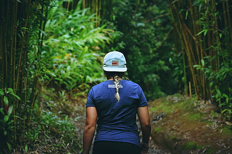 woman walking on road between trees thumbnail