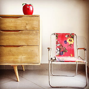 gray metal armchair beside brown wooden 3-drawer chest thumbnail