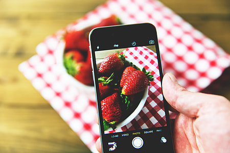 Man taking a photo of fresh strawberry fruit on his mobile iPhone smartphone thumbnail