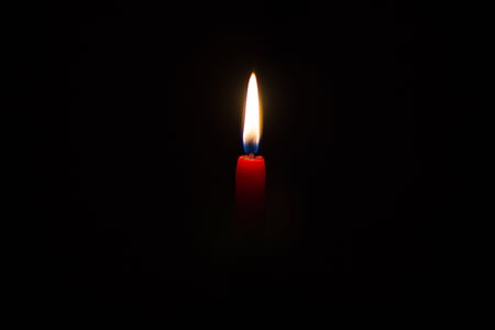 lighted candle against black background thumbnail