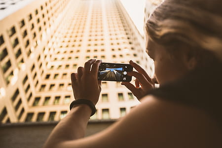 woman taking picture at brown concrete building thumbnail