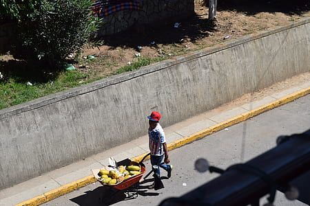 man carrying red wagon down the street thumbnail