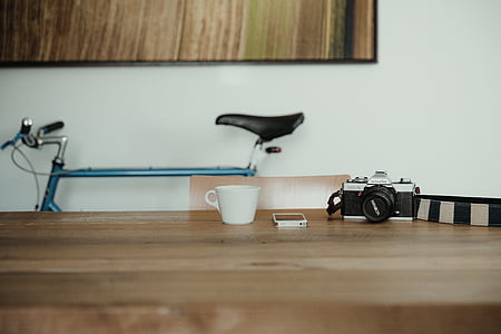 selective focus photography of smartphone on table between cup and camera thumbnail