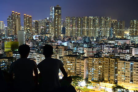 silhouette of two people overlooking city scape at night thumbnail