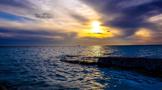 body of water and rock formation under cloudy sky thumbnail