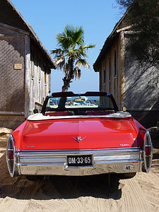 classic red Chevrolet convertible vehicle with DM-33-65 license plate parked infront of wooden buildings at daytime thumbnail