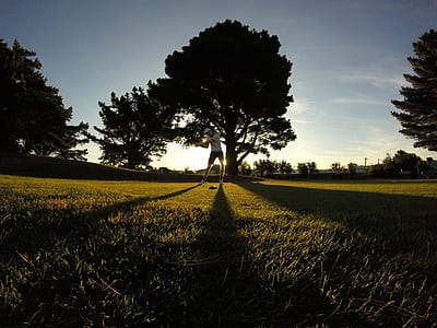man playing golf near trees thumbnail