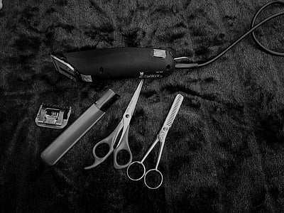 grayscale photography of corded hair clipper and trimming shears on textile thumbnail