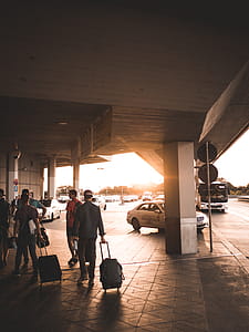 Men Pulling Luggage Bags Along Airport Entrance thumbnail