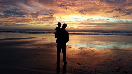 silhouette of man carrying baby beside the seashore thumbnail