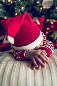 baby lying on ottoman wearing Santa hat thumbnail