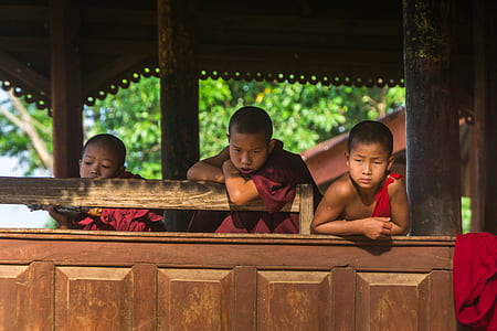 three boys leaning on brown wooden barrier thumbnail