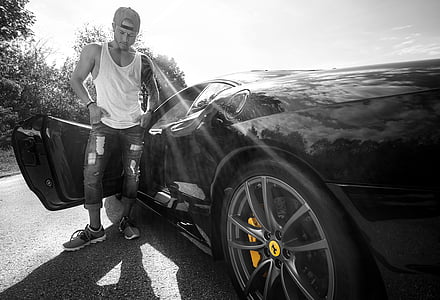 grayscale photography of man standing beside Ferrari sports car thumbnail