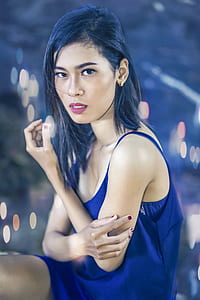 selective focus photography of woman wearing blue spaghetti strap dress holding her arm thumbnail