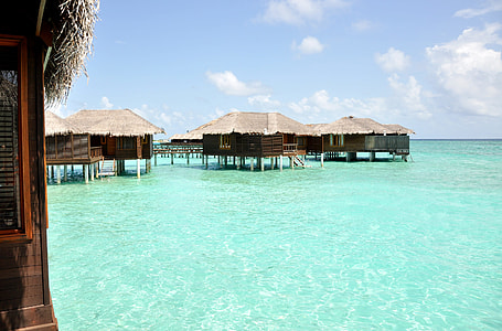 brown wooden bamboo houses in the middle of the sea thumbnail