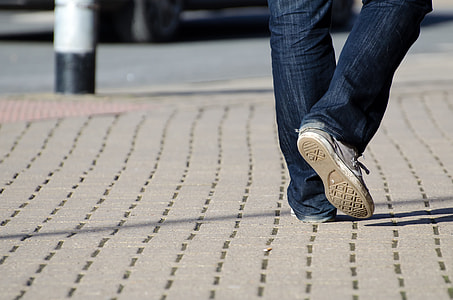 person in blue jeans with white sneakers walking on concrete road thumbnail