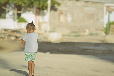 selective focus photography of girl walking near gray concrete wall thumbnail