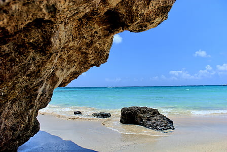 black coastal rocks on white sand shoreline at daytime thumbnail
