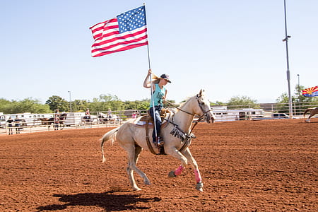 woman riding on horse holding a US flag thumbnail