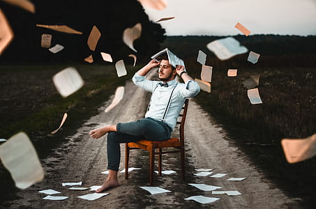 man sitting on brown wooden chair hanging papers thumbnail