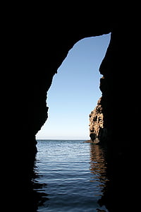 brown rock formation on body of water under blue sky at daytime thumbnail