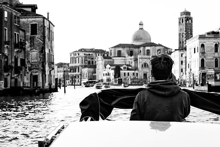 grayscale photo of man standing on boat thumbnail
