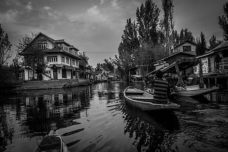 people riding boats near houses grayscale photo thumbnail