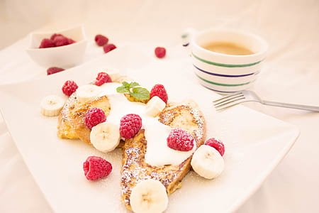 bread with sugar and raspberry on white plate beside cup of beverage thumbnail