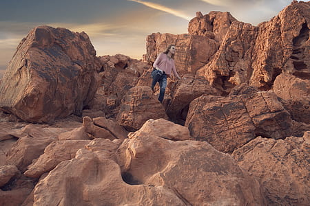 woman in pink top and blue jeans standing on rock thumbnail