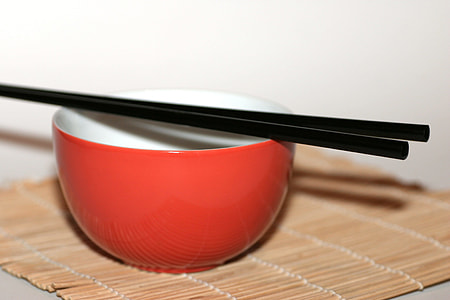 two black chopsticks on red ceramic bowl thumbnail