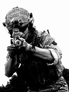 soldier holding rifle with reflex sight wearing full military gear grayscale photo thumbnail