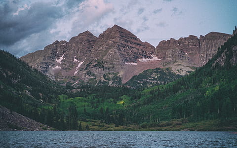 mountain covered with tress surrounded by water during daytime view thumbnail