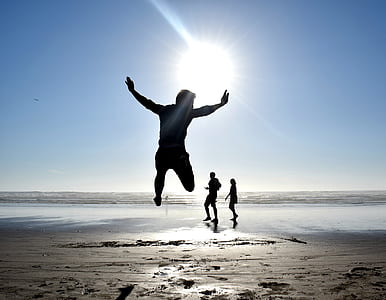 silhouette photography of person jumping against sun in seashore thumbnail