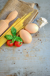 two beige egg near two red tomatoes and beige wooden rolling pin both on gray and beige wooden surface thumbnail