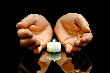 person hand near white candle thumbnail