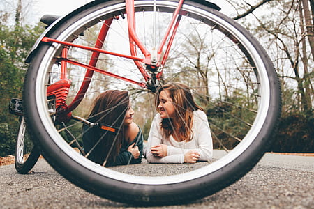 two women lying on road in between trees during daytime thumbnail
