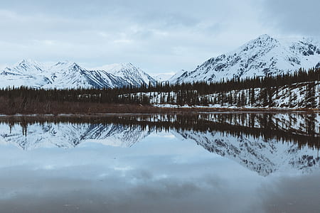 snow caps mountain reflecting on body of water thumbnail