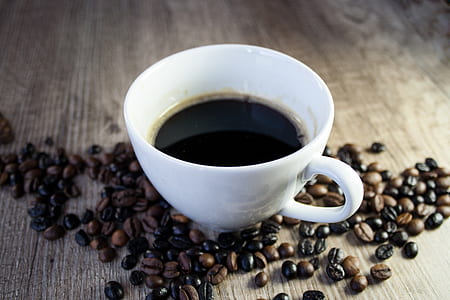 half-filled coffee in white ceramic teacup surrounded with coffee beans thumbnail