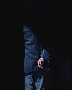 man wearing suit standing near black surface thumbnail