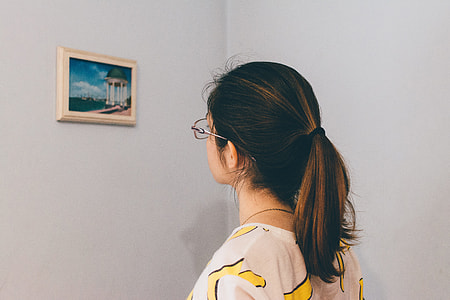 woman in eyeglasses standing and staring at the painting on the wall thumbnail
