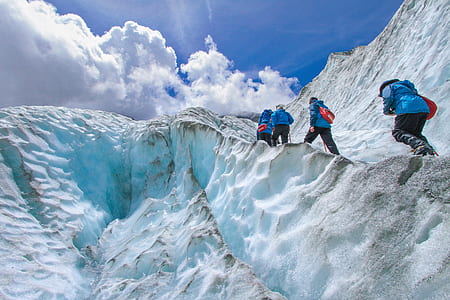 people climbing on snowy mountain under clear blue sky during daytime thumbnail
