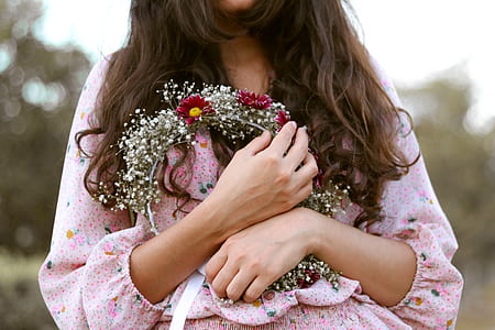 close-up photography of woman holding red and white flower wreath thumbnail