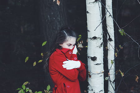 woman covering her mouth with her jacket near birch tree thumbnail