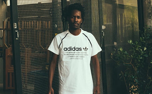 man wearing white adidas crew-neck t-shirt standing near door thumbnail