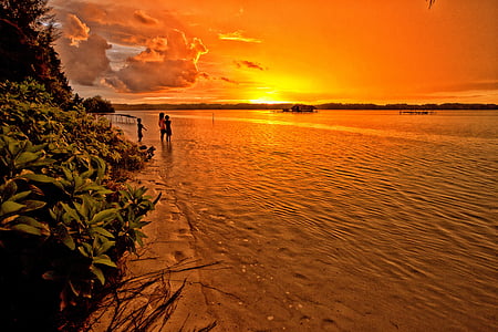 children standing on gray sand next to beach during sunset thumbnail