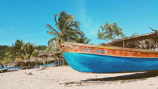 brown and blue wooden canoe on sand under blue sky during daytime thumbnail
